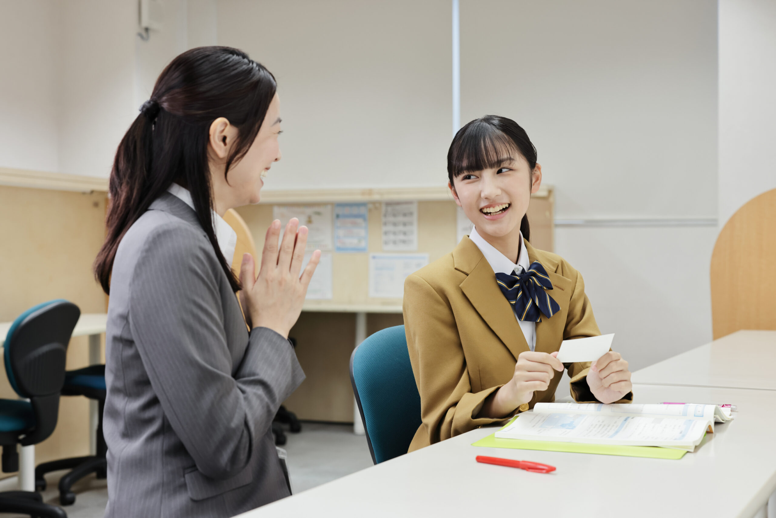 個別指導塾での１対１の指導風景。問題が解けたことに女子生徒は喜んでおり、女性講師も一緒に喜んでいます。